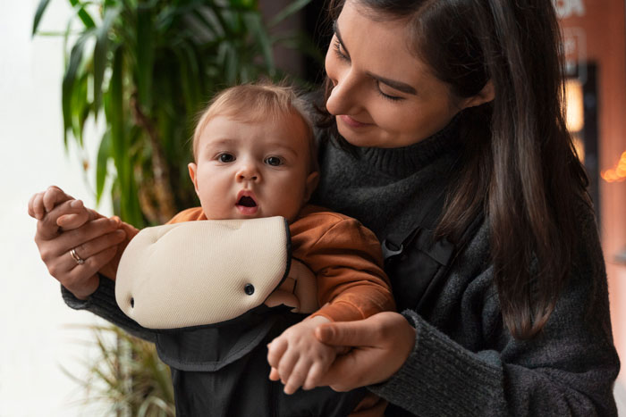 Mother lovingly holding baby indoors, gently supporting with both hands.