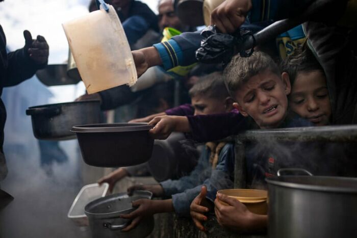 Children reaching out with bowls for food, emphasizing sustainability in daily life through impactful photography.