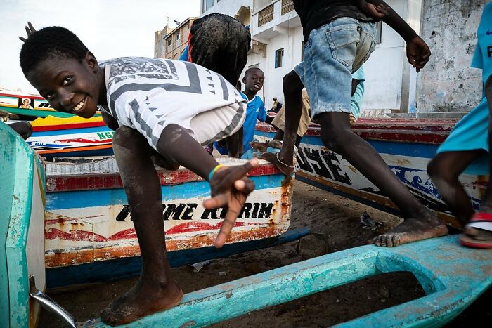 Children playing energetically on colorful boats, captured by photographer Ivan Margot.