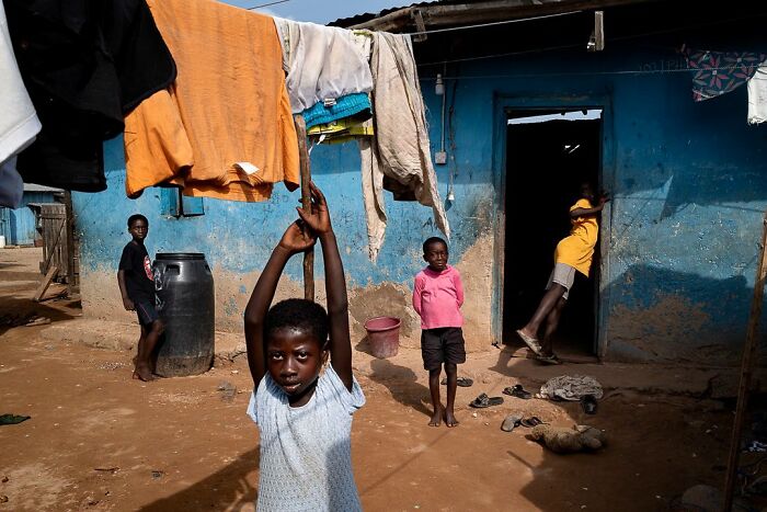 Vibrant photograph by Ivan Margot featuring children playing in a rural setting with colorful clothes hanging overhead.