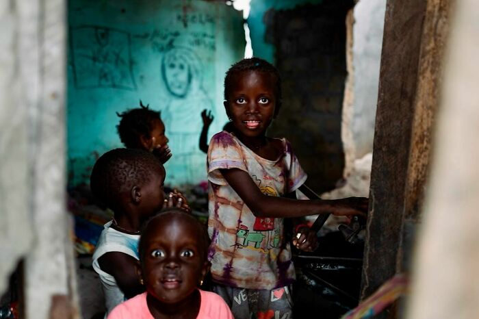 Children smiling in a vibrant photograph by Ivan Margot, set in a rustic, colorful room.