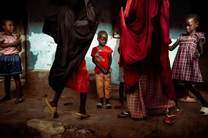 Colorful street scene with children and adults in dynamic movement, capturing vibrant photography by Ivan Margot.