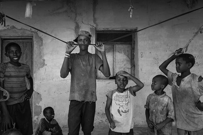 Children posing playfully in a rustic setting, captured in Ivan Margot’s photography.