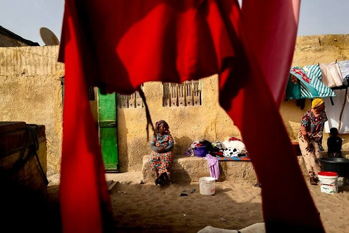 Vibrant photograph by Ivan Margot, depicting a candid moment in a colorful, sunlit courtyard scene.