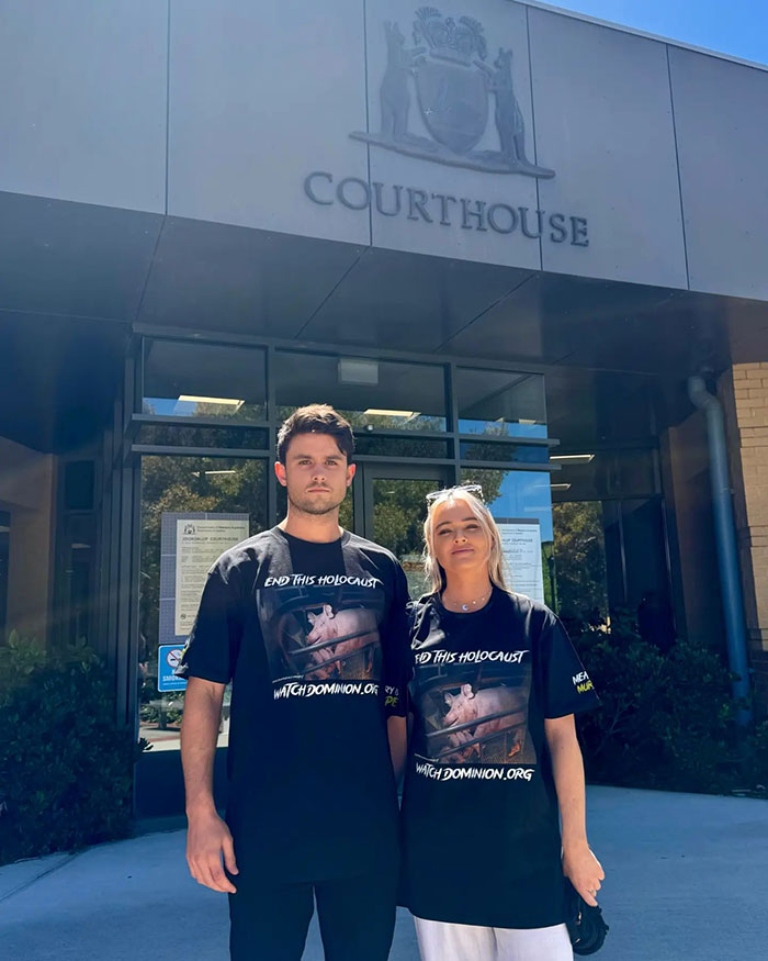 Vegan activist couple stands outside courthouse advocating against animal slavery.