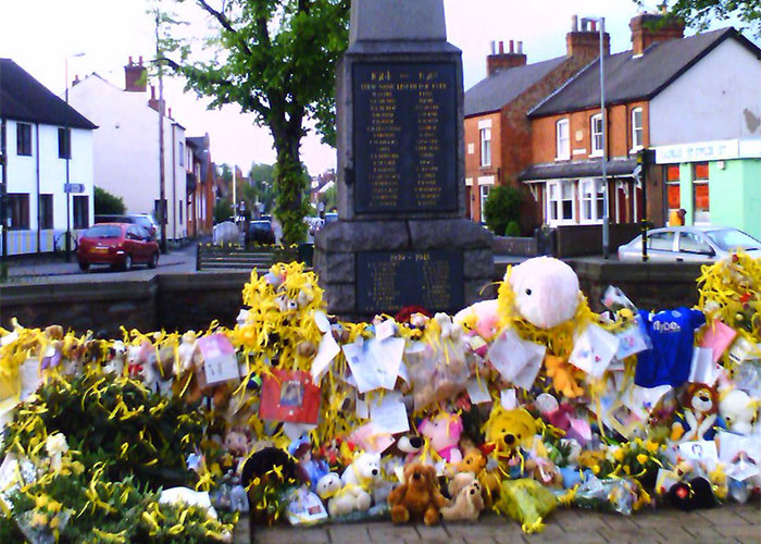 Memorial with flowers and stuffed animals, hinting at an unexplainable mystery in a residential neighborhood.