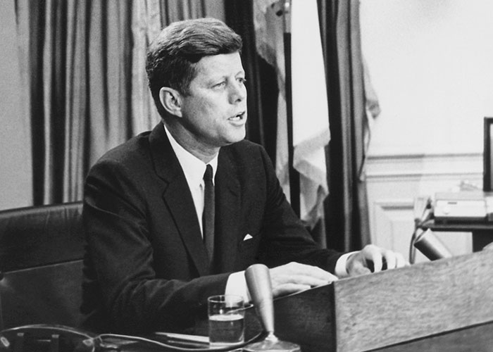 A man in a suit speaking at a podium, related to an unexplainable mystery.