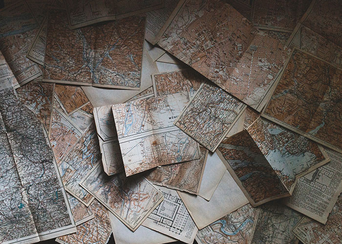 Scattered vintage maps related to an unexplainable mystery, showcasing intricate geographical details and exploration paths.