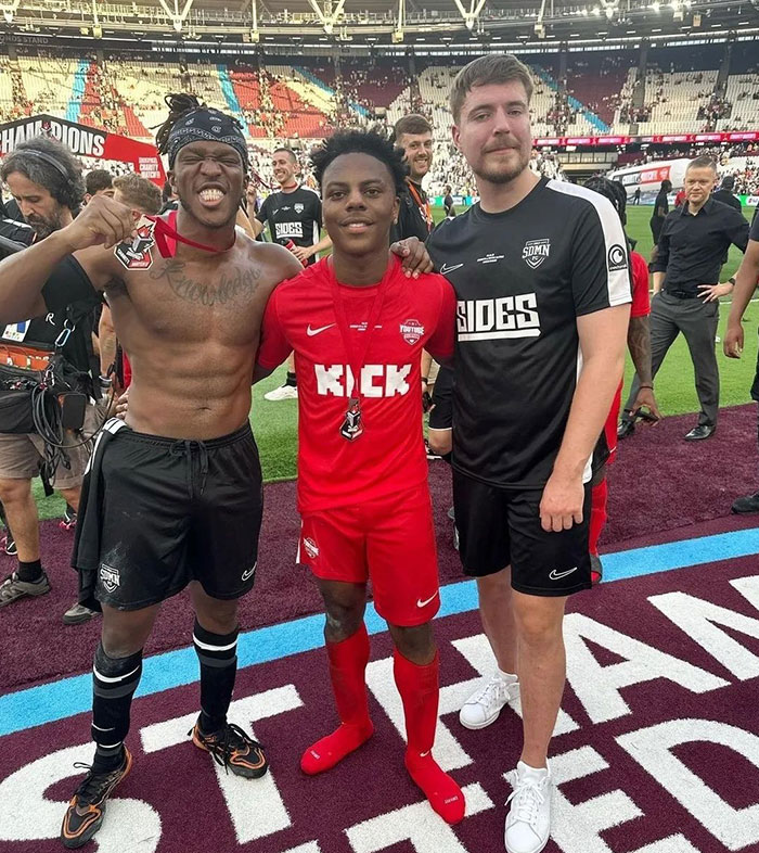 Kai Cenat standing with two people on a football field after a game, showcasing camaraderie; a discussion around Kai Cenat’s height trends online.