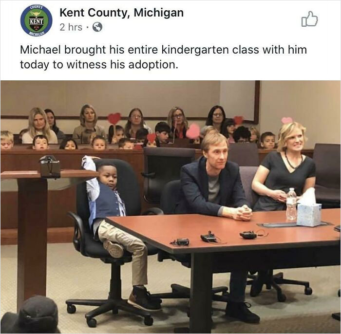 Child with classmates and adults in courtroom, celebrating a heartwarming adoption moment.