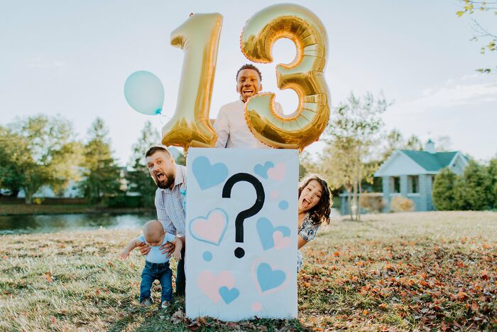 Family joyfully celebrating adoption with balloons and a colorful question mark sign outdoors.