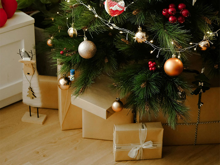 Christmas tree with ornaments and wrapped gifts, highlighting holiday decor.