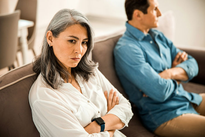 Couple sitting on a couch with arms crossed, illustrating tension and conflict, related to a second chance in a marriage.