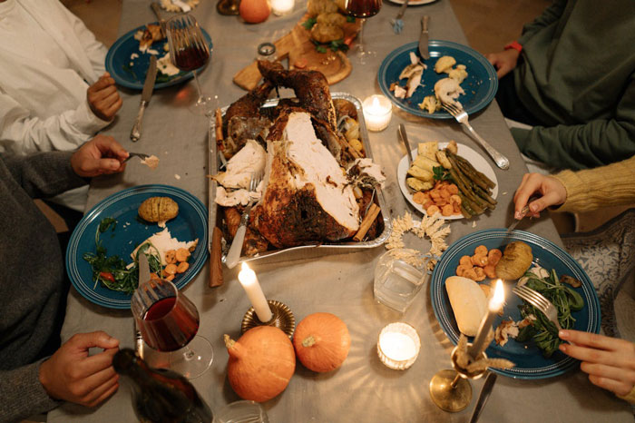 Thanksgiving dinner table with turkey, side dishes, and candles.