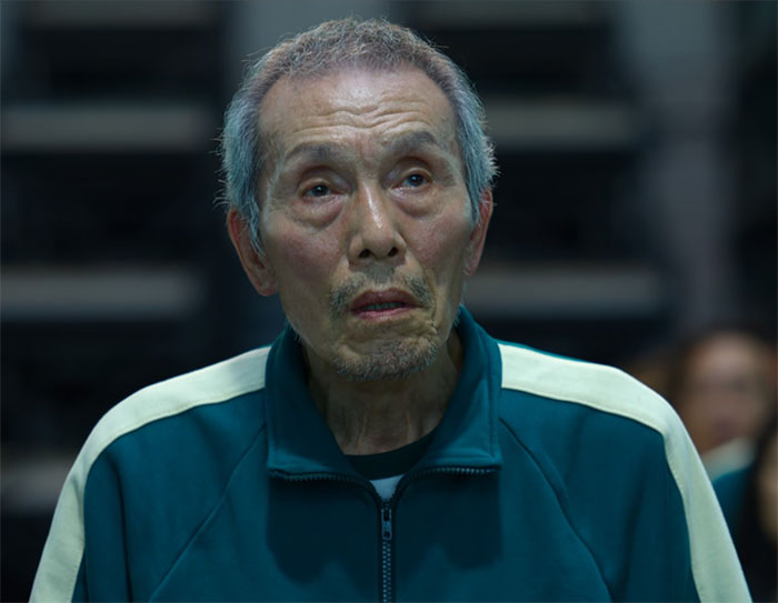 Elderly man in a green and white tracksuit from Squid Game.