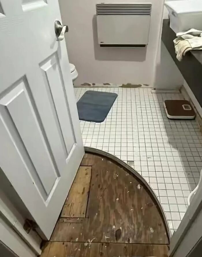 Bathroom construction fail with curved tile cutout missing from the floor.