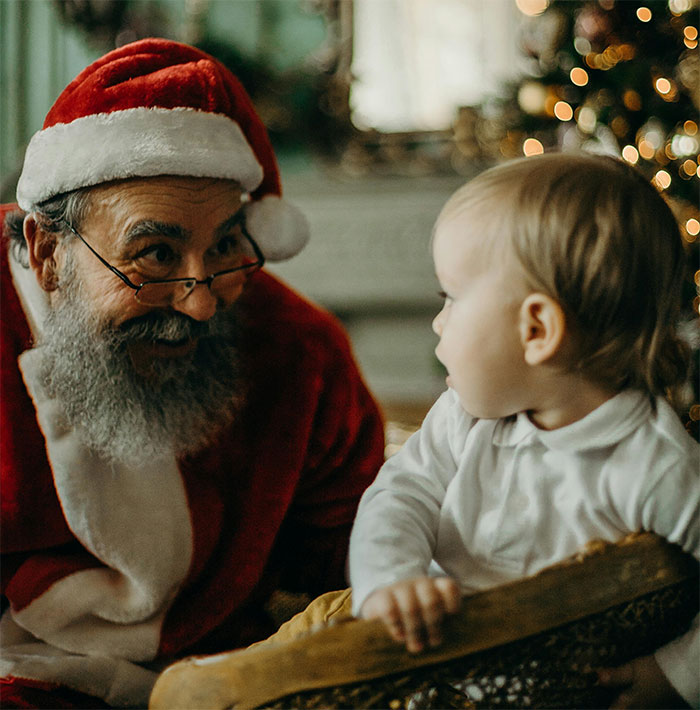 Santa Claus interacting with a curious child, festive Christmas setting in the background.