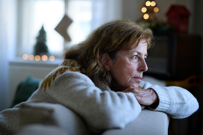 Woman looking upset while leaning on a sofa, reflecting on gifts and family issues during holidays.