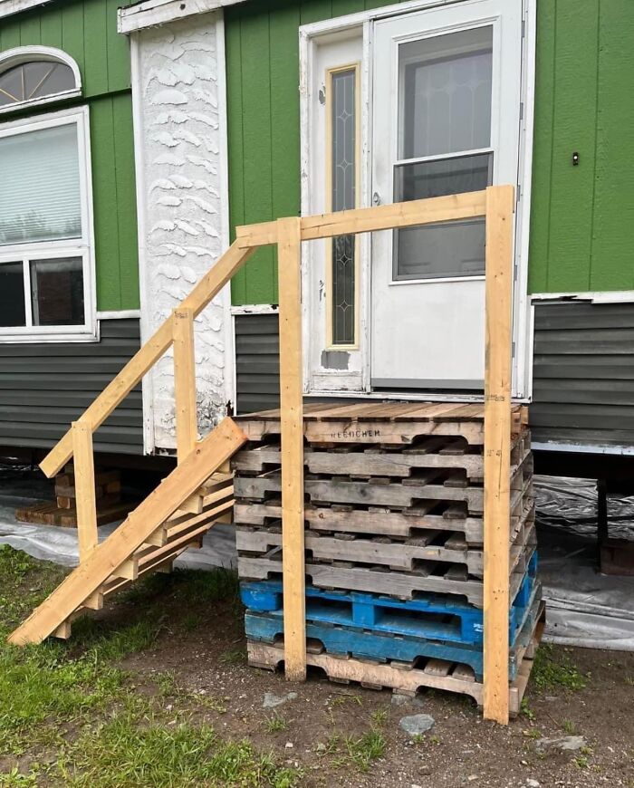 Funny construction fail with makeshift stairs made of wooden pallets leading to a house door.