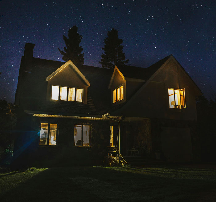 Cozy house at night with lights on, suggesting importance of home security measures.