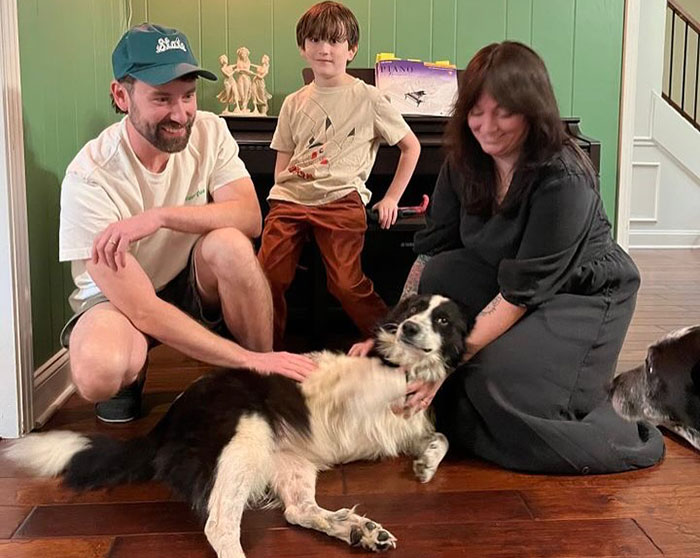 Family with a rescued dog, petting and smiling in a cozy living room setting.