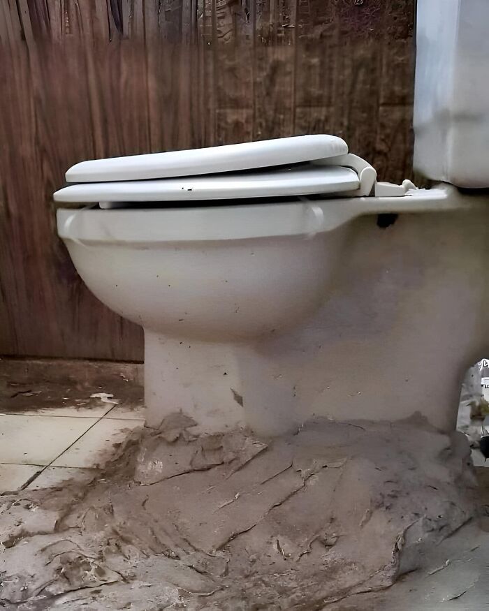 Funny construction fail with a poorly installed toilet, surrounded by uneven cement work.