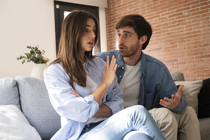 Couple having an intense conversation on a couch, possibly about hidden birth control pills.