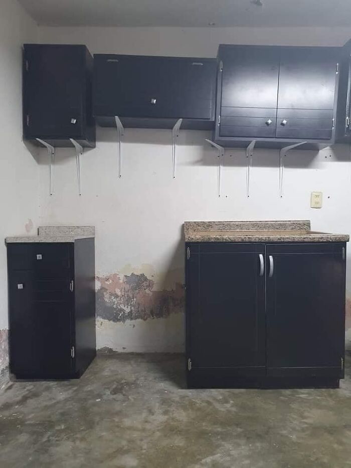 Funny cheap construction fail with misaligned black kitchen cabinets and uneven wall paint.