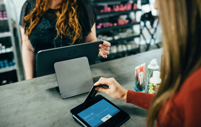 Person using a card reader at a store counter, symbolizing reasons for being fired.