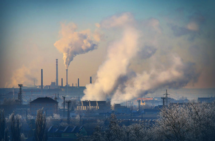 Industrial landscape with factories emitting smoke into the sky, reflecting environmental impact and pollution concerns.