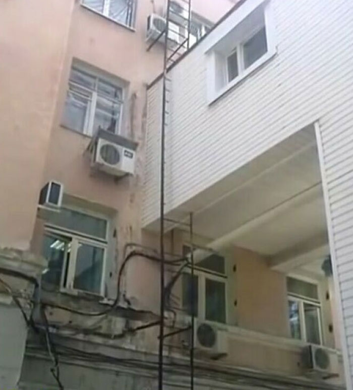 Misaligned ladder leading to a building window, showcasing construction mistakes.