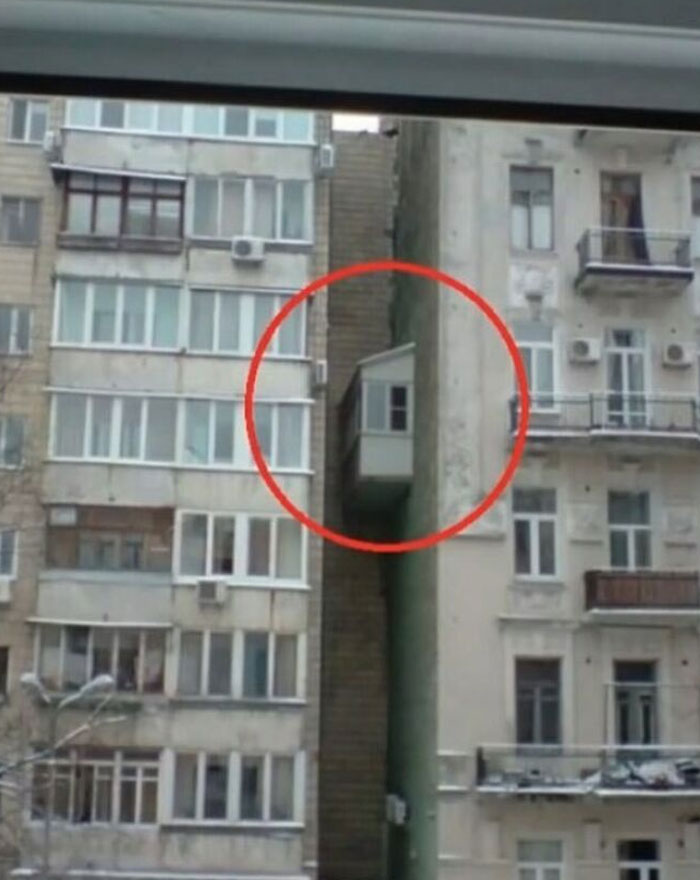 Construction fail with a balcony built between two buildings, highlighting a hilarious design mistake.