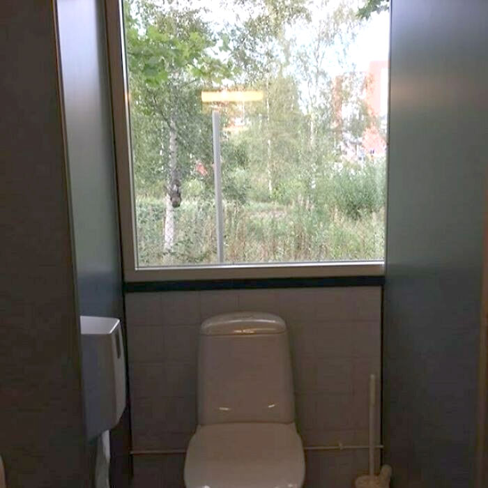 Construction fail: Toilet installed directly in front of a large window, overlooking a scenic outdoor view.