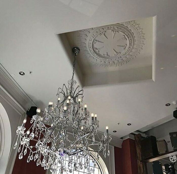 Chandelier misaligned with ceiling feature, illustrating a construction fail.