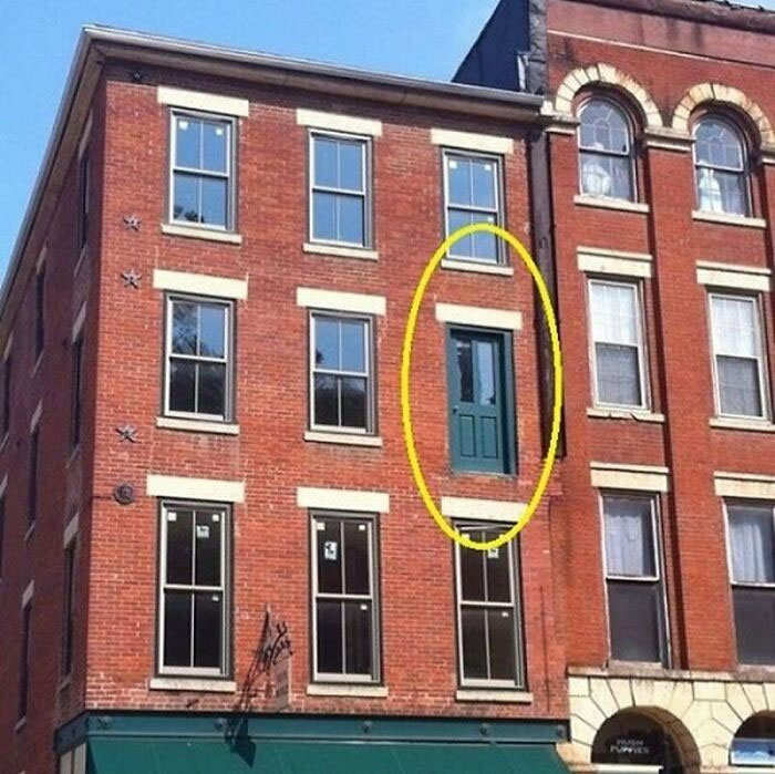 Construction workers installed a door opening to nowhere on a brick building's second floor.