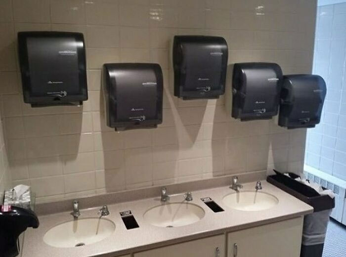 Construction fail: paper towel dispensers misaligned with sinks in a restroom.