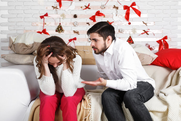 Couple having a heated argument during Christmas, with festive decorations in the background.