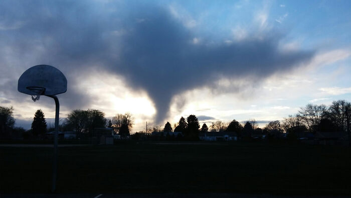 Dark cloud resembling a tornado over a basketball court at sunset, capturing worst things happen wedding scenario.