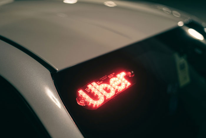 Uber sign on a car window, highlighting security measures for rideshare users.