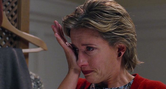 A woman in a red sweater, wiping tears, depicting a strong female protagonist in an emotional scene.