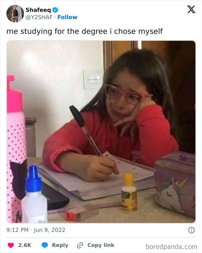 Child studying with a notebook and pen, wearing pink glasses, looking tired. Humor and relatable science meme.