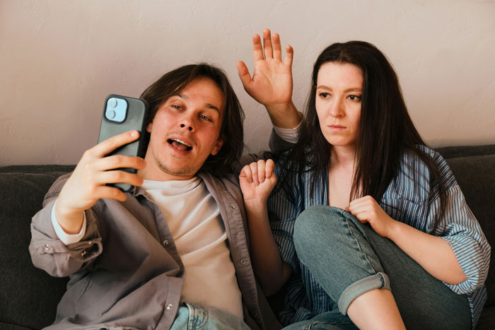 Two people on a couch, one holding a smartphone, demonstrating Gen A's interaction with technology.