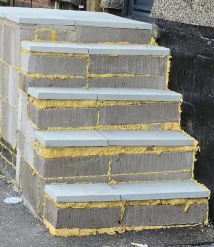 DIY concrete steps with uneven yellow mortar, illustrating a funny cheap construction fail.