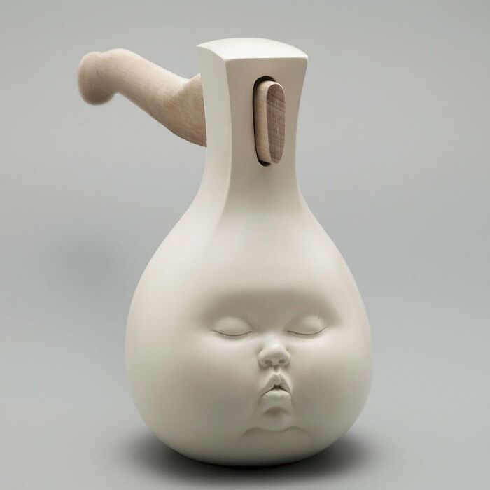 Surreal art sculpture featuring a white ceramic axe with a child's face blended into the design.