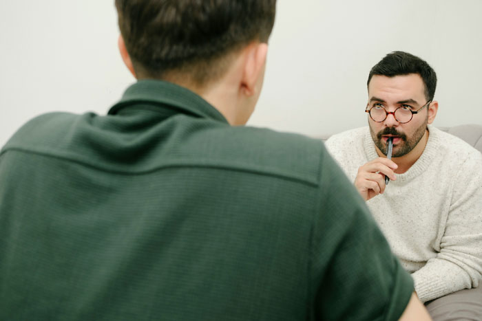 Person with glasses pondering during a conversation, related to reasons for being fired.