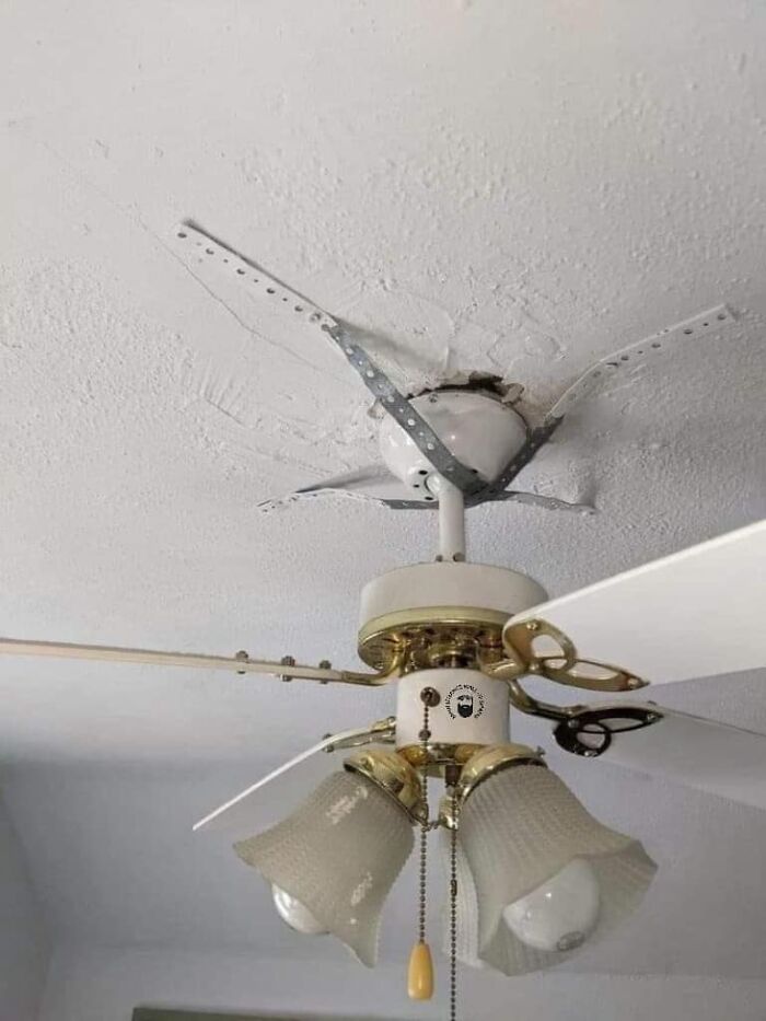 Ceiling fan humorously held up by metal braces, showcasing a cheap construction fail.