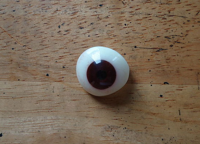 A realistic fake eye on a wooden surface, associated with surprising speeding reasons.