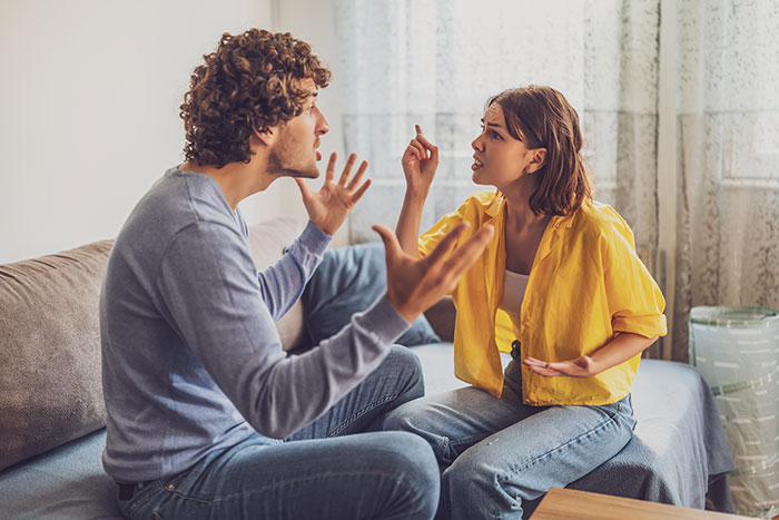 Couple arguing in living room, expressing frustration and upset emotions.