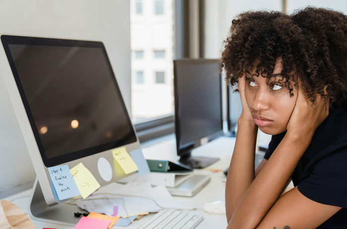 Person looking frustrated at a desk with a computer, highlighting the need for better security measures.