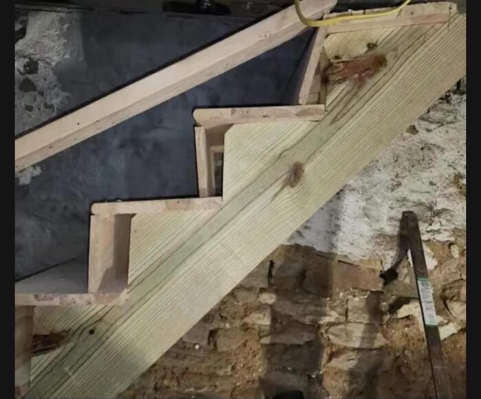 Funny cheap construction fails with misaligned wooden staircase steps in a basement.